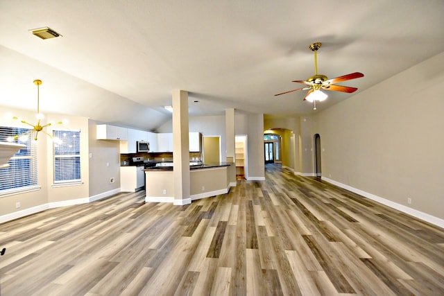 unfurnished living room with lofted ceiling, ceiling fan with notable chandelier, and light hardwood / wood-style floors