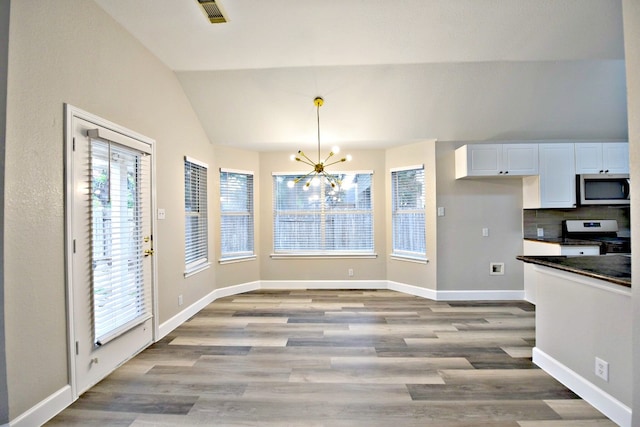 unfurnished dining area featuring light wood-type flooring, a chandelier, and vaulted ceiling