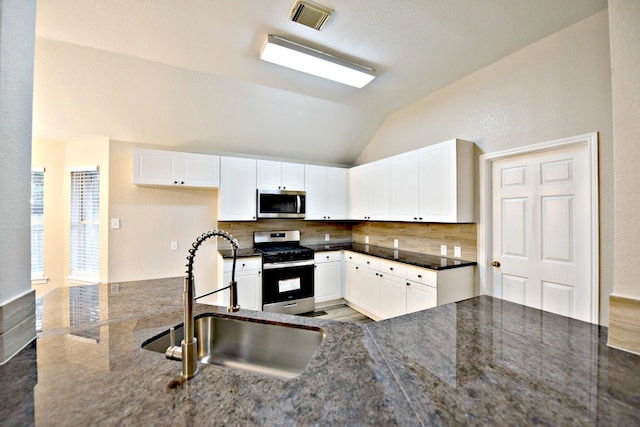 kitchen featuring appliances with stainless steel finishes, sink, decorative backsplash, lofted ceiling, and dark stone counters