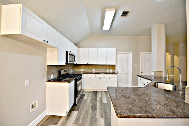 kitchen featuring light wood-type flooring, white cabinetry, stainless steel appliances, sink, and decorative backsplash