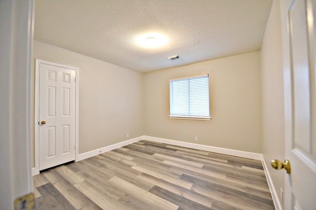 spare room with light hardwood / wood-style floors and a textured ceiling