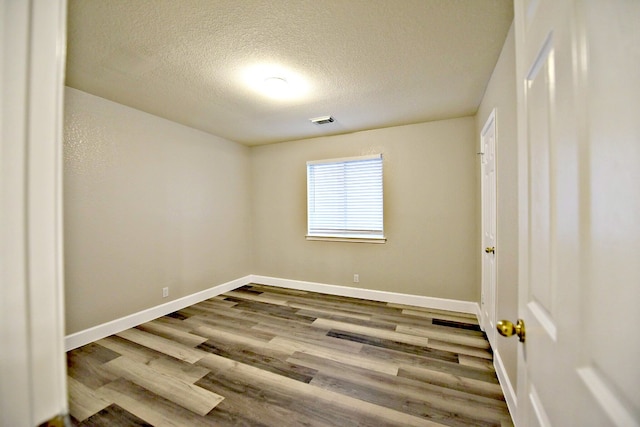 spare room featuring a textured ceiling and light hardwood / wood-style floors