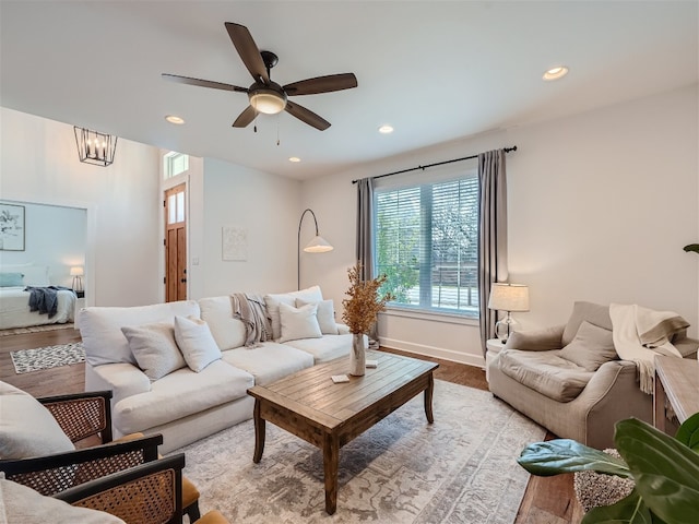 living room with light hardwood / wood-style flooring and ceiling fan with notable chandelier