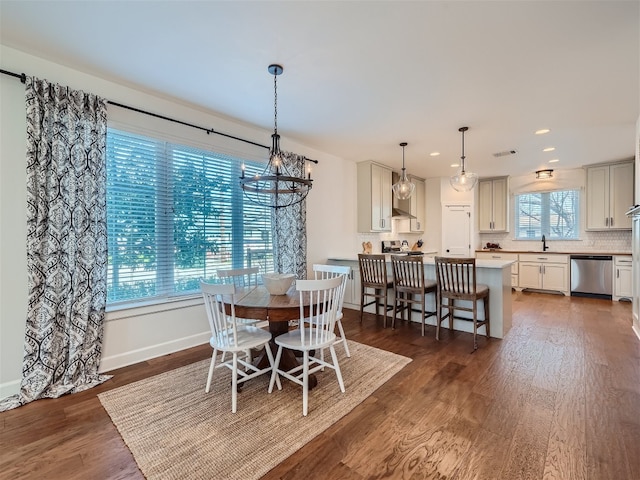 dining space featuring sink, dark wood-type flooring, and an inviting chandelier