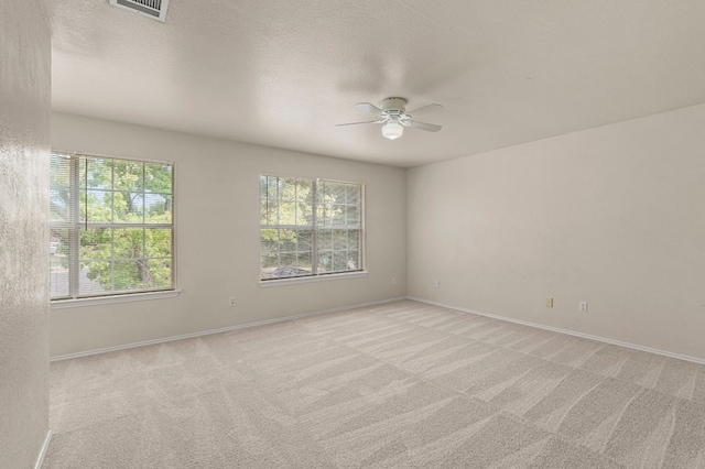 spare room featuring light colored carpet, ceiling fan, and a textured ceiling