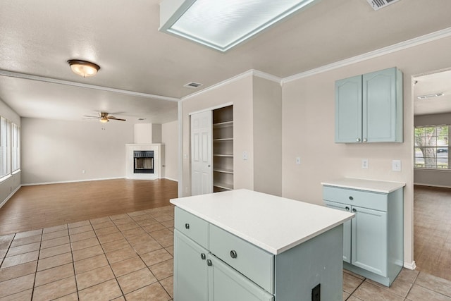 kitchen featuring ornamental molding, light hardwood / wood-style flooring, a kitchen island, and ceiling fan