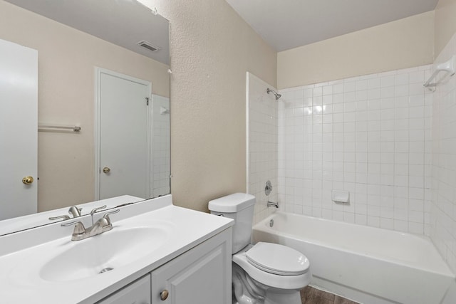 full bathroom featuring hardwood / wood-style floors, tiled shower / bath, toilet, and vanity