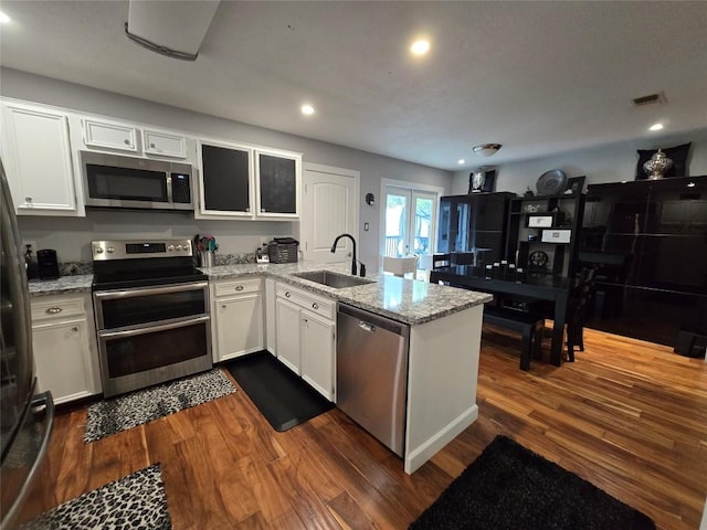 kitchen featuring sink, stainless steel appliances, dark hardwood / wood-style floors, kitchen peninsula, and white cabinets