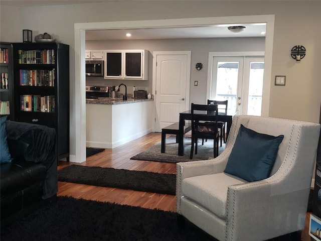 living room featuring french doors, light hardwood / wood-style flooring, and sink