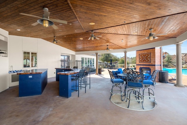 view of patio / terrace with an outdoor bar, area for grilling, ceiling fan, and a large fireplace