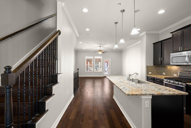 kitchen featuring decorative light fixtures, dark hardwood / wood-style flooring, appliances with stainless steel finishes, a kitchen island with sink, and sink