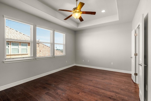 spare room with plenty of natural light, ceiling fan, dark hardwood / wood-style floors, and a raised ceiling