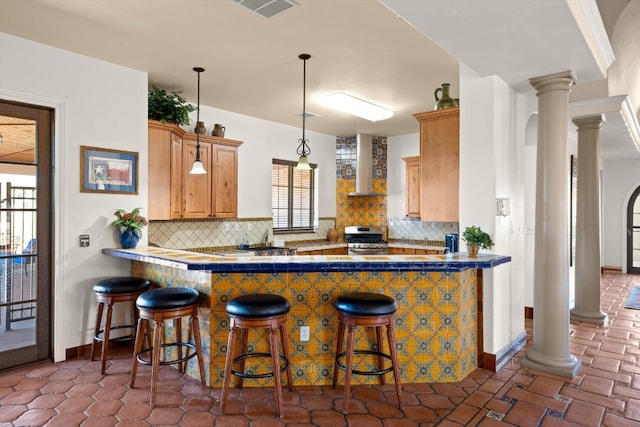 kitchen with decorative backsplash, wall chimney range hood, kitchen peninsula, stainless steel range with gas cooktop, and a breakfast bar