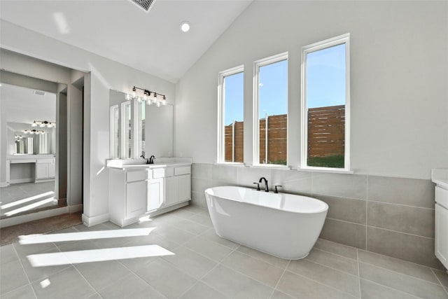 bathroom with tile patterned flooring, a bath, and lofted ceiling