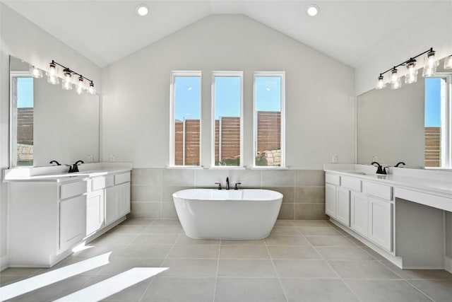 bathroom with lofted ceiling, a washtub, tile walls, and tile patterned flooring