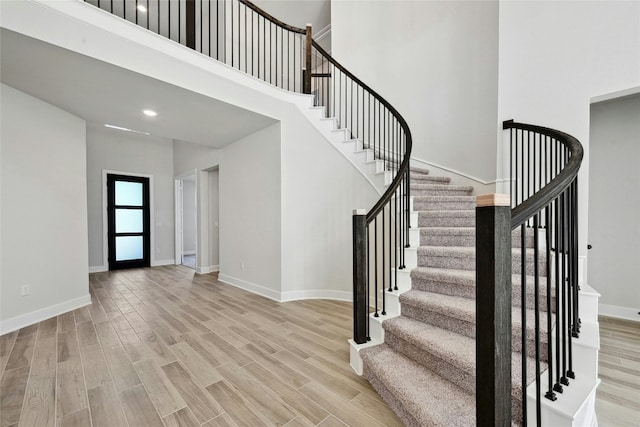 stairs with a high ceiling and wood-type flooring