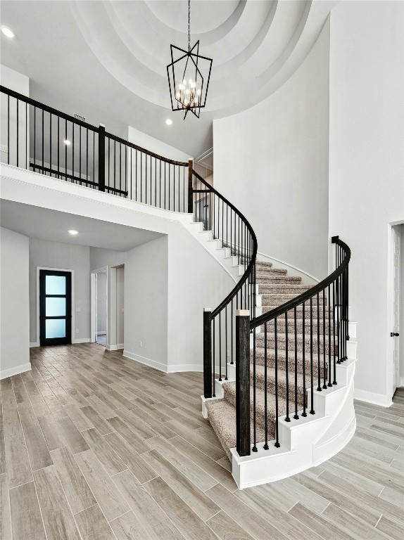 stairs featuring a raised ceiling, wood-type flooring, and a high ceiling