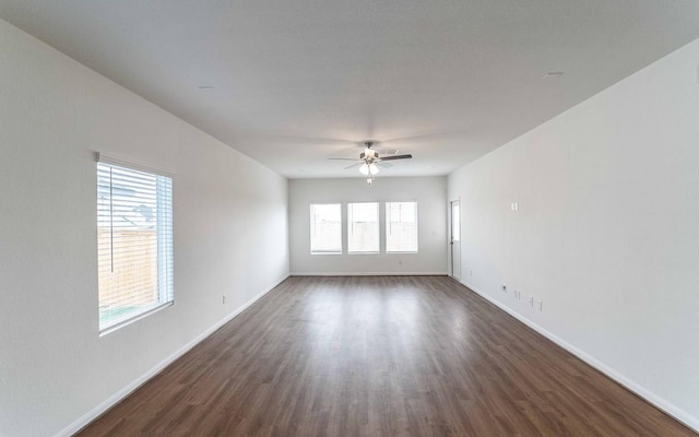 empty room featuring ceiling fan, a healthy amount of sunlight, and dark hardwood / wood-style flooring