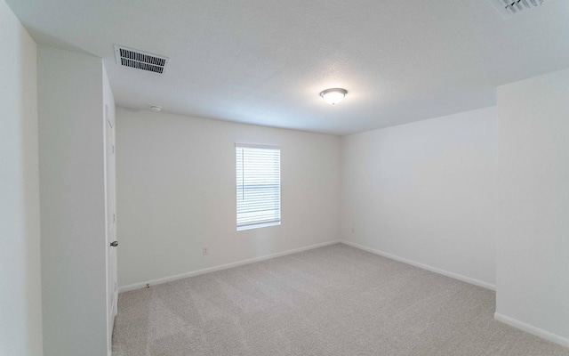 empty room featuring a textured ceiling and light colored carpet