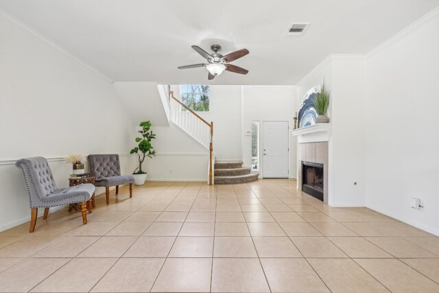 sitting room with ornamental molding, a tiled fireplace, ceiling fan, and light tile patterned floors