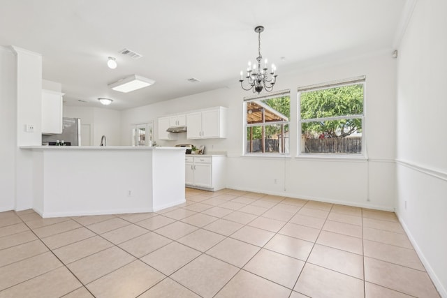 kitchen with white cabinets, light tile patterned flooring, ornamental molding, kitchen peninsula, and a chandelier