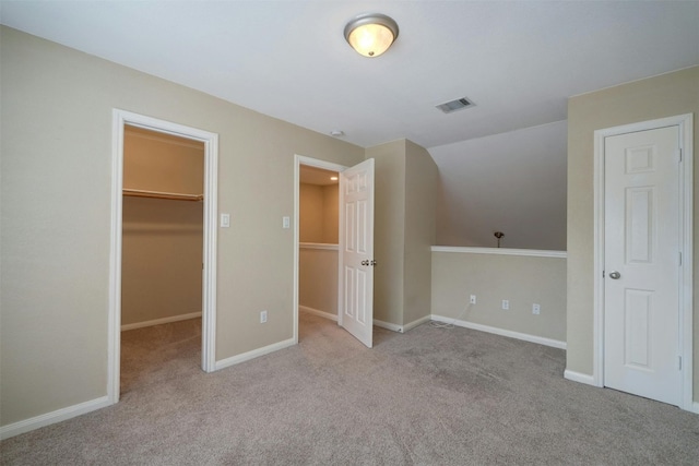 unfurnished bedroom featuring light carpet, a walk in closet, and a closet