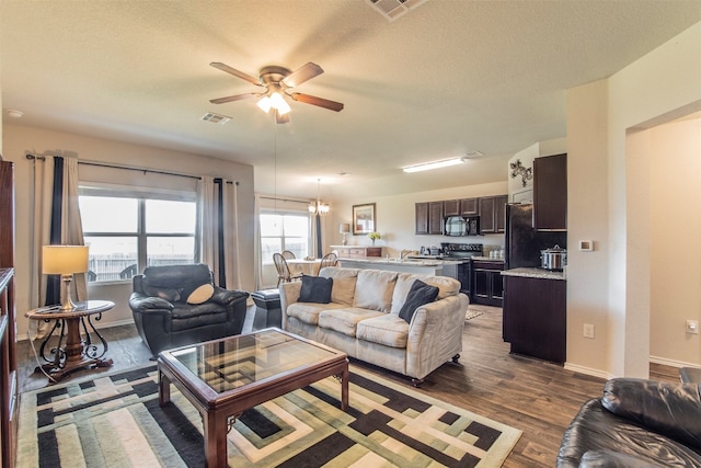 living room with a textured ceiling, a wealth of natural light, wood-type flooring, and ceiling fan