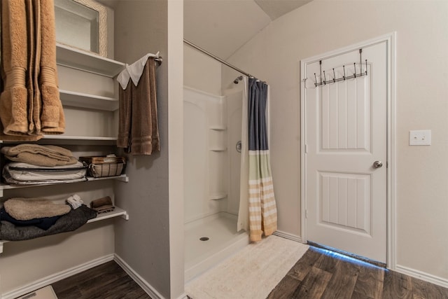 bathroom featuring lofted ceiling, hardwood / wood-style floors, and walk in shower