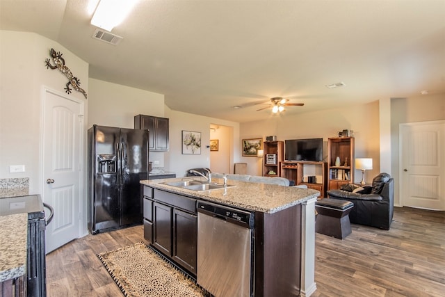 kitchen with stainless steel appliances, an island with sink, ceiling fan, sink, and dark brown cabinetry