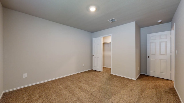 unfurnished bedroom with carpet flooring, a closet, and a spacious closet