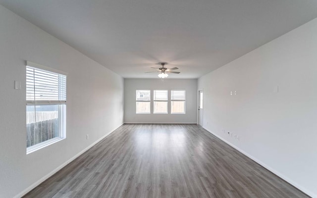 empty room featuring plenty of natural light, ceiling fan, and dark hardwood / wood-style floors