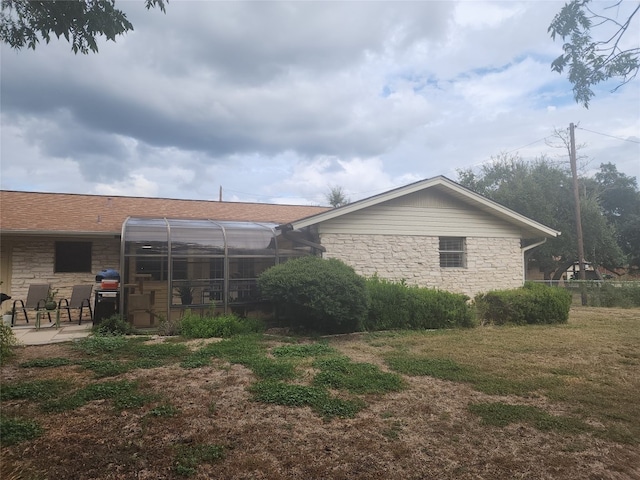 rear view of house featuring a patio, a lanai, and a lawn