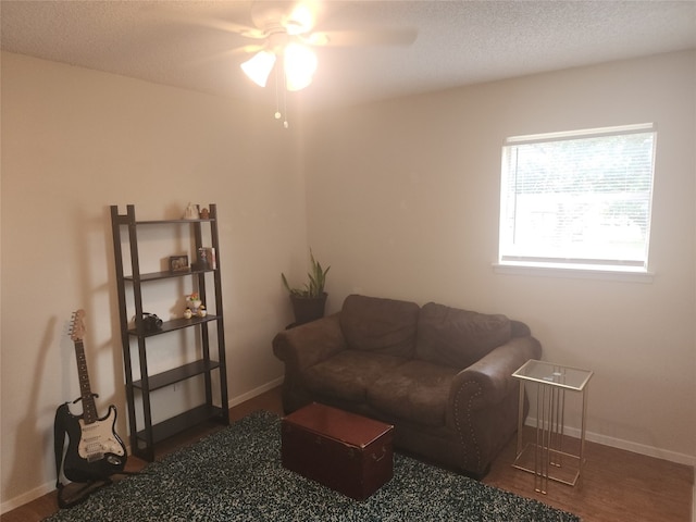 living room featuring ceiling fan, a textured ceiling, and dark hardwood / wood-style floors