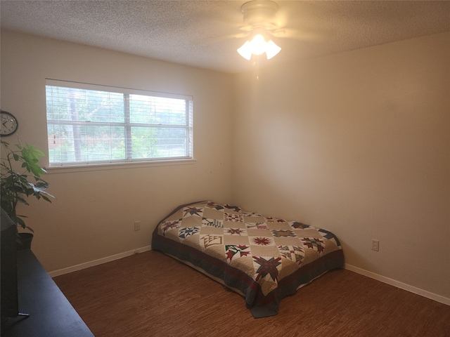 bedroom with ceiling fan, a textured ceiling, and dark hardwood / wood-style flooring