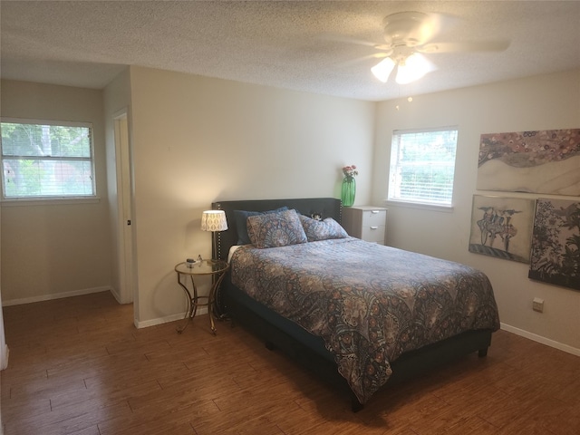 bedroom with dark wood-type flooring, ceiling fan, and a textured ceiling