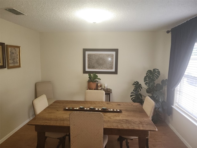 dining area with a textured ceiling and dark hardwood / wood-style flooring