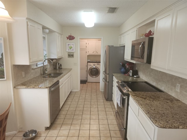 kitchen with washer / clothes dryer, sink, stainless steel appliances, white cabinets, and decorative backsplash