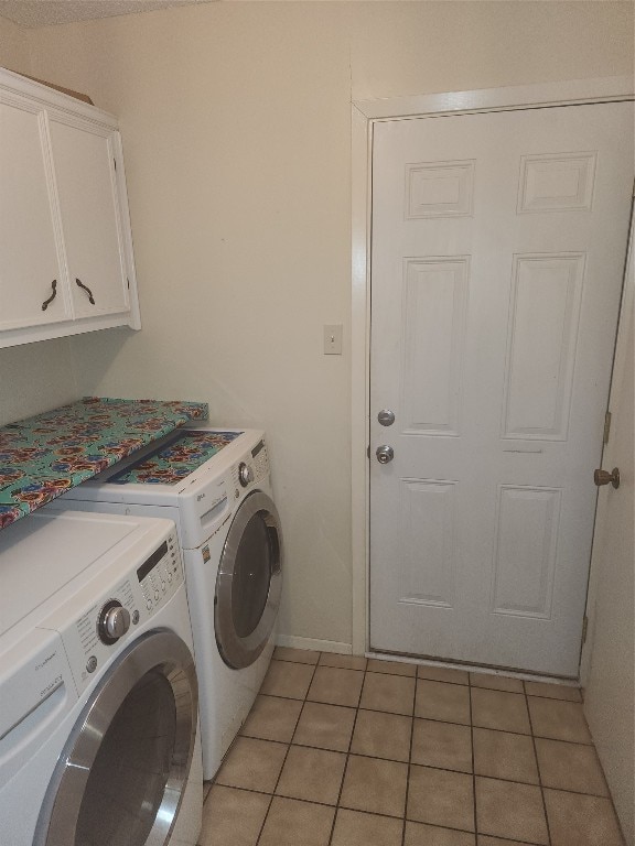 clothes washing area featuring cabinets, independent washer and dryer, and light tile patterned flooring