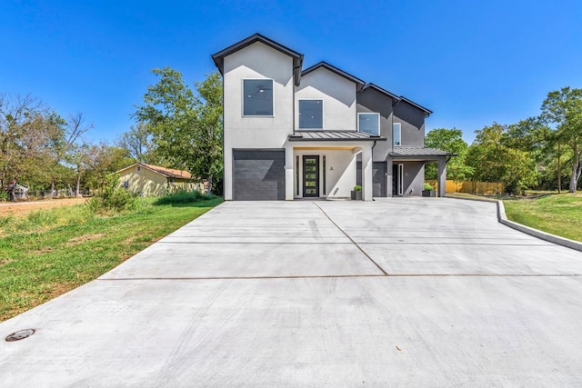 view of front facade featuring metal roof, an attached garage, driveway, a standing seam roof, and a front yard