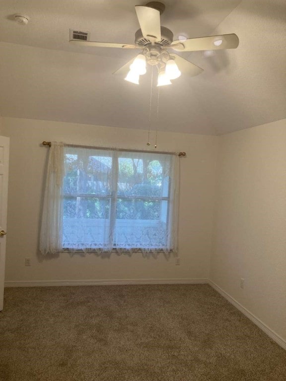 empty room with vaulted ceiling, ceiling fan, and carpet floors