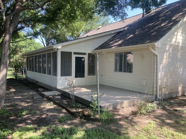 rear view of property with a sunroom and a patio