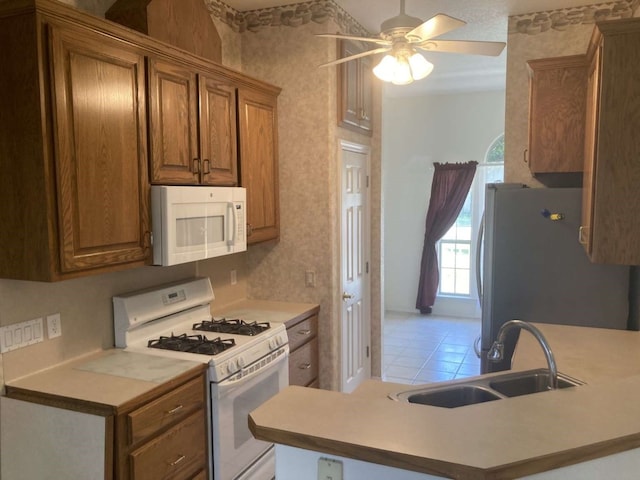 kitchen featuring white appliances, ceiling fan, kitchen peninsula, and sink