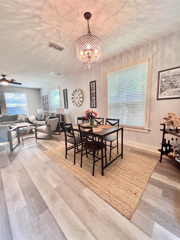 dining space featuring light hardwood / wood-style flooring and ceiling fan with notable chandelier