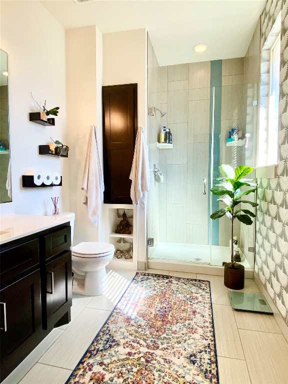 bathroom with walk in shower, vanity, toilet, and tile patterned floors