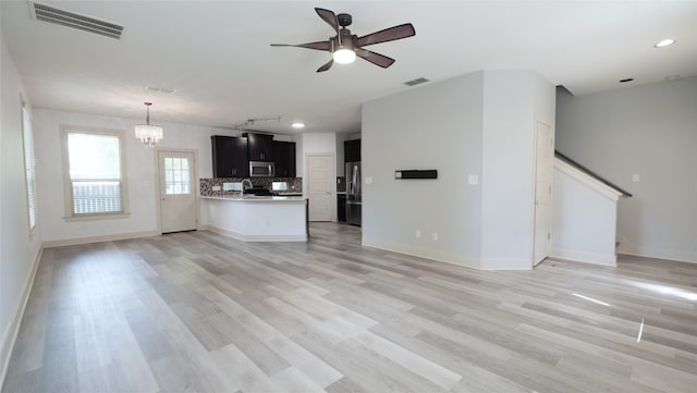 interior space with sink, ceiling fan with notable chandelier, and light hardwood / wood-style floors