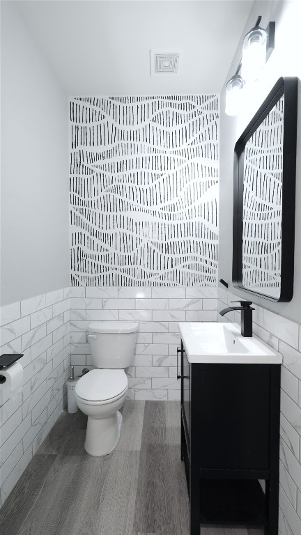 bathroom featuring vanity, tile walls, and toilet