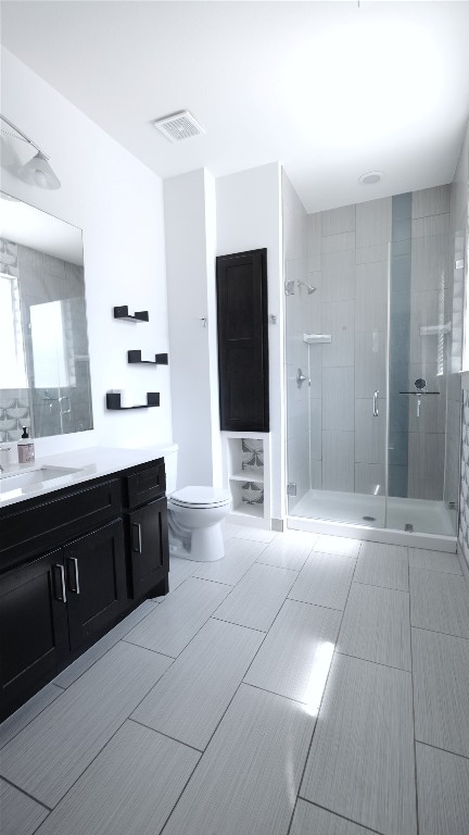 bathroom with vanity, a shower with shower door, and toilet