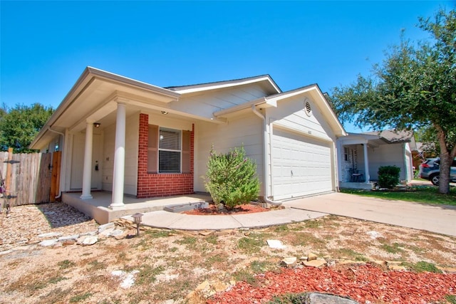 ranch-style house featuring fence, covered porch, a garage, and driveway