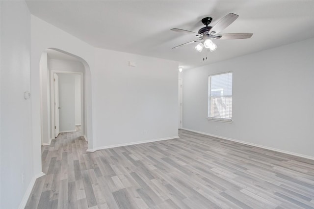 unfurnished room with light wood-type flooring, arched walkways, baseboards, and ceiling fan