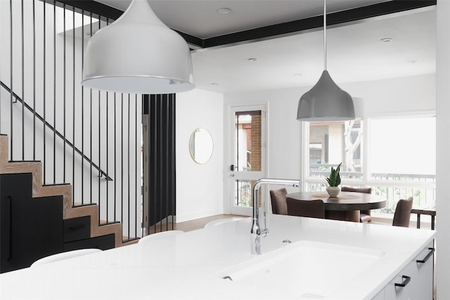 interior space featuring pendant lighting, light countertops, a sink, and white cabinets